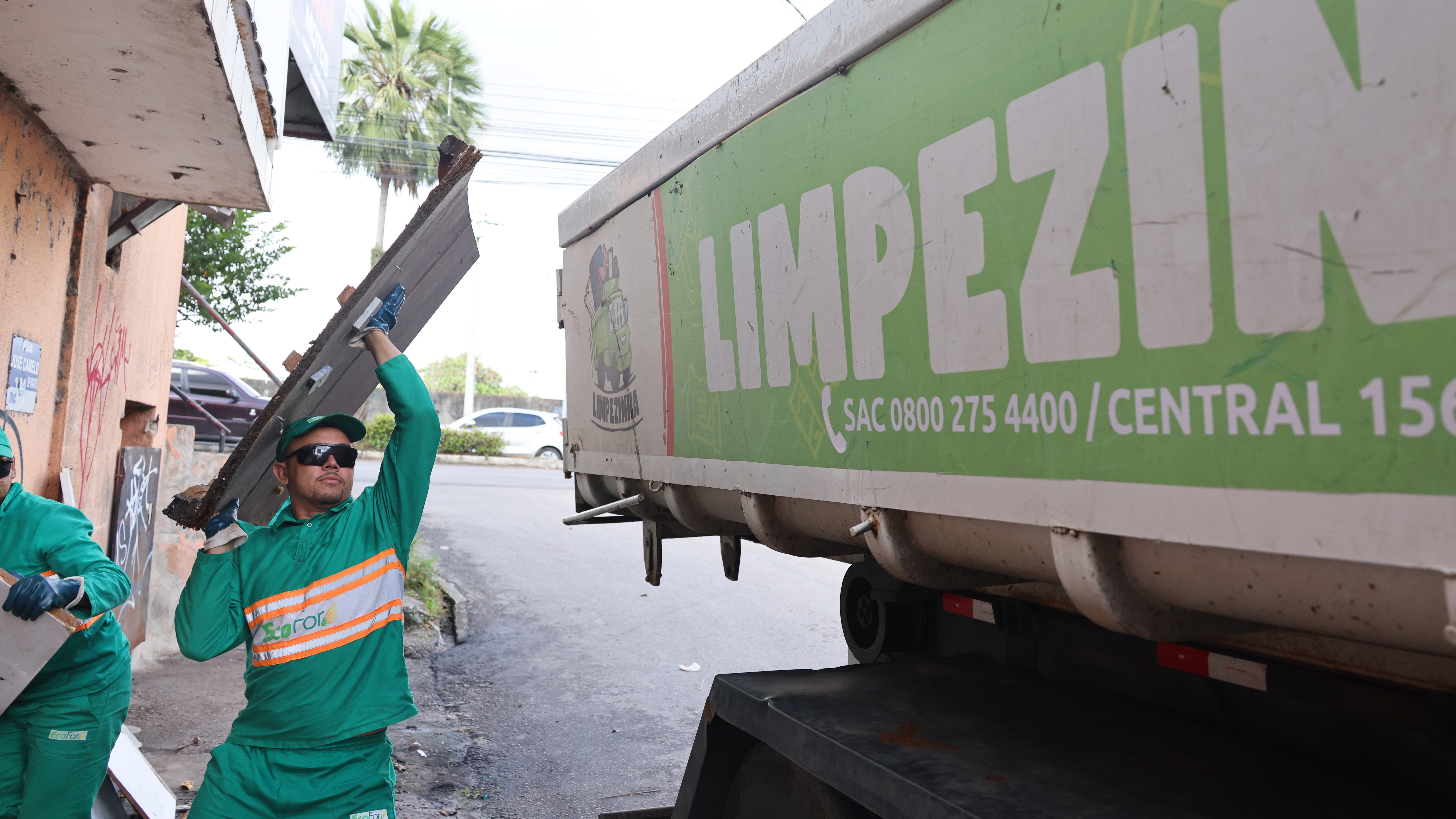 homem jogando pedaço de madeira no caminhão limpezinha